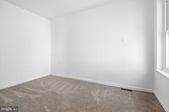carpeted spare room featuring visible vents and baseboards