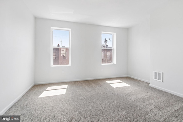 carpeted spare room featuring visible vents and baseboards
