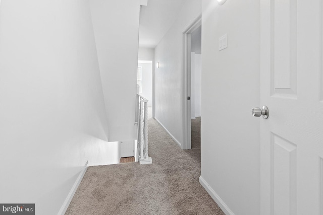corridor with baseboards, an upstairs landing, and carpet flooring