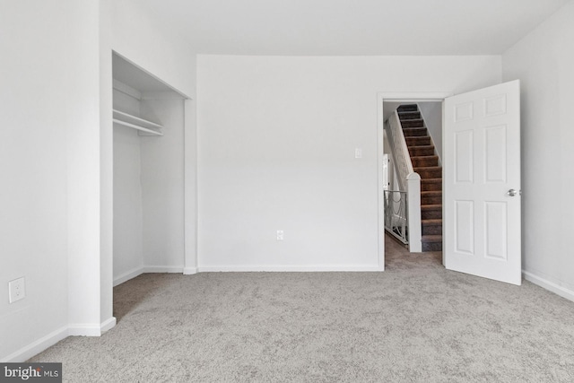 unfurnished bedroom with a closet, carpet flooring, baseboards, and a spacious closet