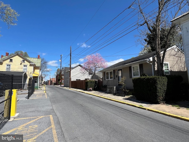view of street with curbs, a residential view, street lights, and sidewalks