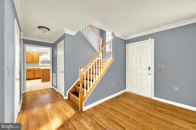 entryway featuring light wood-type flooring, baseboards, stairway, and crown molding