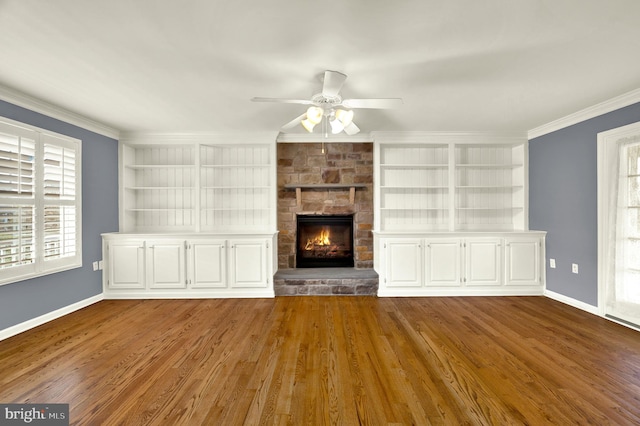 unfurnished living room featuring baseboards, crown molding, built in shelves, and a ceiling fan
