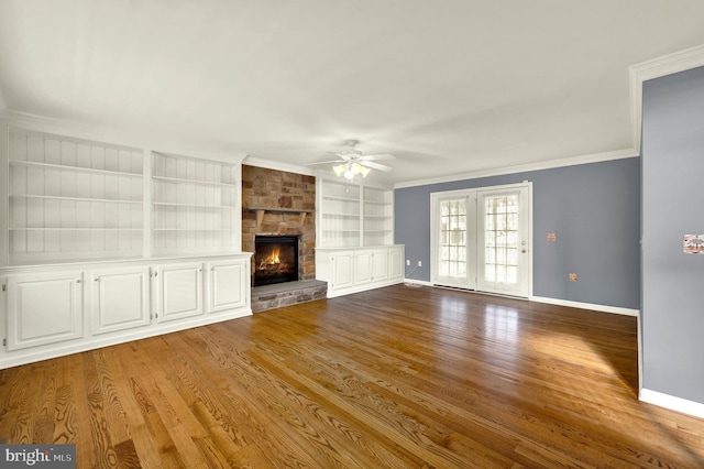 unfurnished living room featuring baseboards, built in features, a ceiling fan, wood finished floors, and ornamental molding