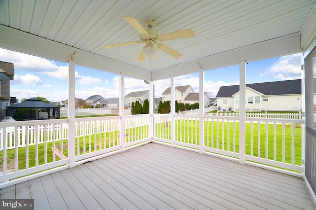 unfurnished sunroom with a ceiling fan and a residential view