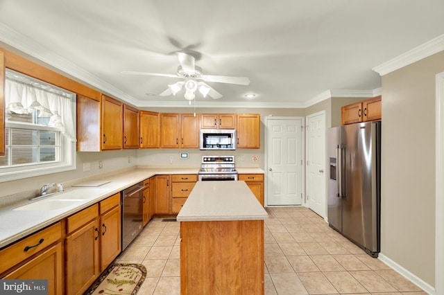 kitchen with a ceiling fan, a sink, light countertops, appliances with stainless steel finishes, and a kitchen island
