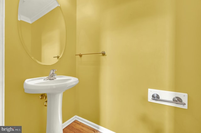 bathroom featuring baseboards, ornamental molding, and wood finished floors