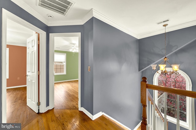 hallway with wood finished floors, visible vents, and an upstairs landing
