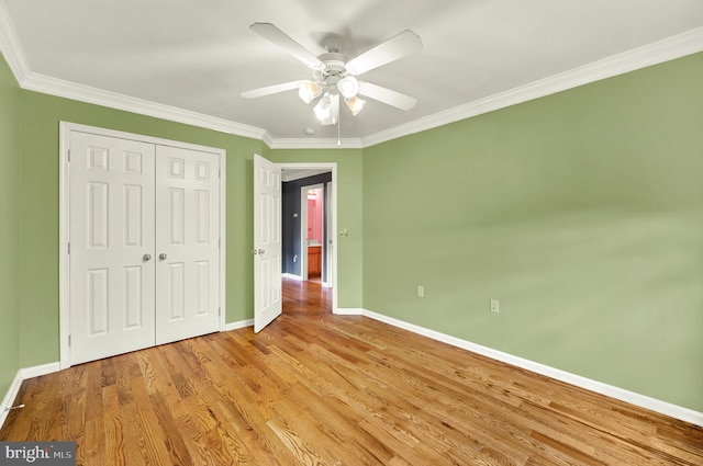 unfurnished bedroom featuring wood finished floors, baseboards, a closet, and ornamental molding