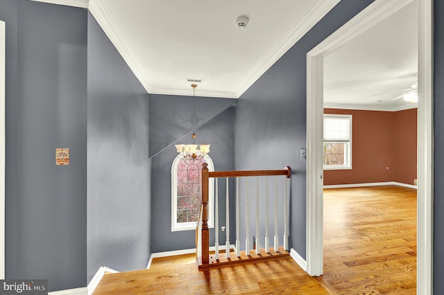 interior space with wood finished floors, crown molding, baseboards, and ceiling fan with notable chandelier