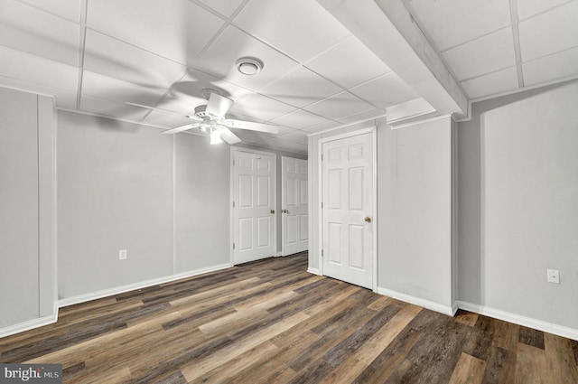 basement featuring baseboards, a ceiling fan, wood finished floors, and a paneled ceiling