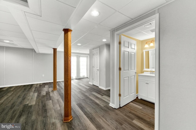 basement featuring a drop ceiling, baseboards, recessed lighting, and dark wood finished floors
