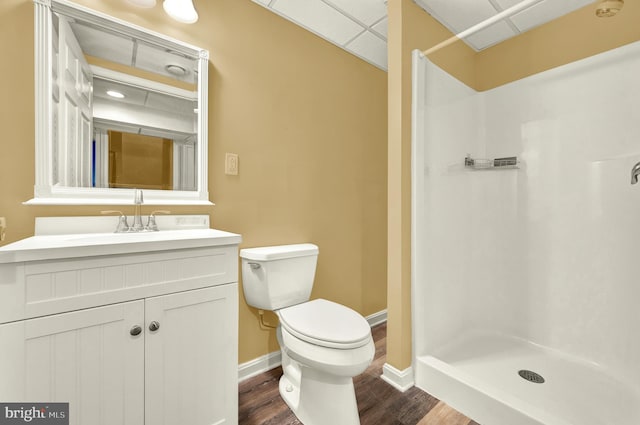 bathroom featuring baseboards, toilet, wood finished floors, and a stall shower