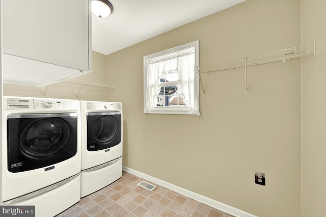 laundry room featuring washing machine and clothes dryer, cabinet space, visible vents, and baseboards