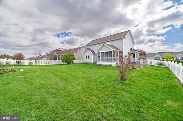rear view of house featuring a sunroom, a fenced backyard, and a lawn
