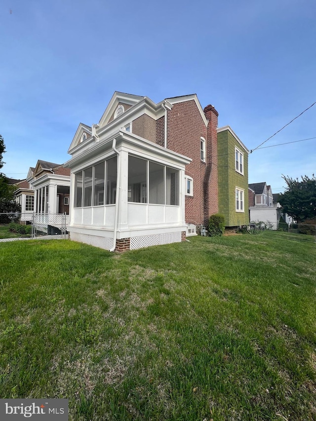 back of property with a sunroom and a lawn