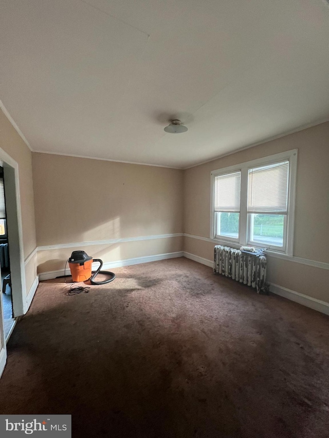 empty room with carpet flooring, baseboards, ornamental molding, and radiator
