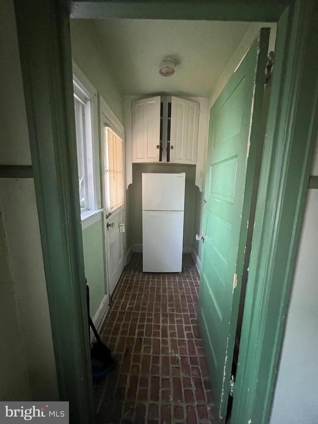 laundry room with baseboards and brick floor