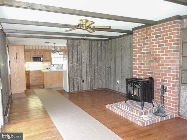 2560 Sardonyx Dr, Chambersburg, PA 17202 - living area featuring a wood stove, light wood-style flooring, a ceiling fan, wooden walls, and beam ceiling
