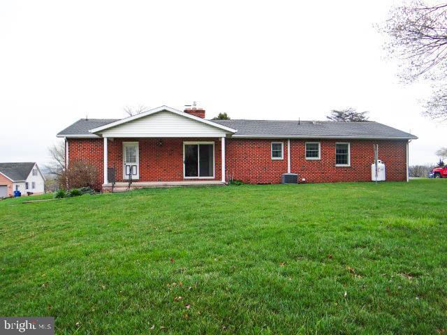 2560 Sardonyx Dr, Chambersburg, PA 17202 - rear view of house featuring brick siding, central air condition unit, a chimney, and a lawn