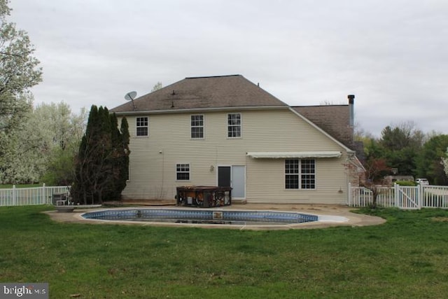 rear view of property featuring a lawn, a fenced backyard, a fenced in pool, and a hot tub
