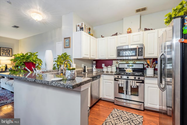 4129 Fountainside Ln Unit 202, Fairfax, VA 22030 - kitchen with stainless steel appliances, a peninsula, white cabinetry, and wood finished floors