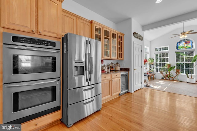 kitchen with lofted ceiling, stainless steel appliances, wine cooler, and light wood-style floors