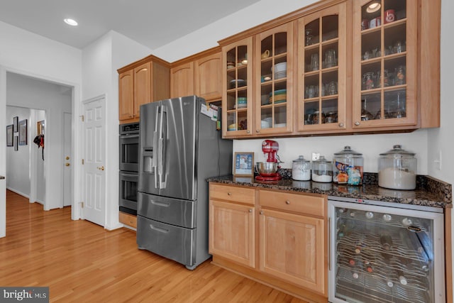 kitchen featuring wine cooler, light wood-style flooring, dark stone countertops, dobule oven black, and stainless steel refrigerator with ice dispenser