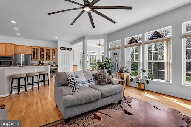 living room with light wood-style floors, ceiling fan, and a healthy amount of sunlight