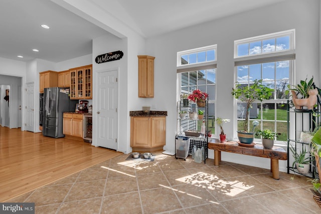 interior space featuring recessed lighting, wine cooler, light brown cabinets, freestanding refrigerator, and glass insert cabinets