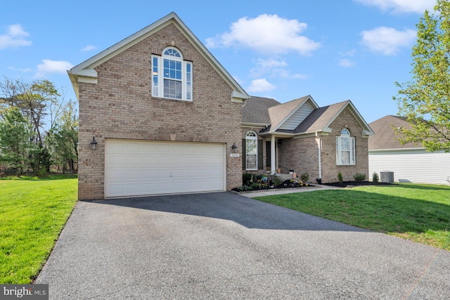 traditional home with a front lawn, aphalt driveway, an attached garage, cooling unit, and brick siding