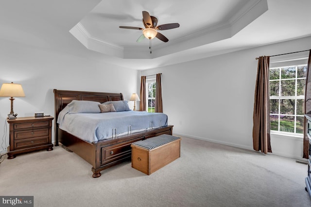 bedroom with light carpet, a ceiling fan, a tray ceiling, and ornamental molding