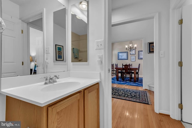 bathroom with wood finished floors, vanity, and a notable chandelier