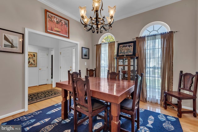 dining room with an inviting chandelier, crown molding, wood finished floors, and plenty of natural light