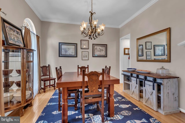 dining room featuring light wood-style flooring, an inviting chandelier, and crown molding