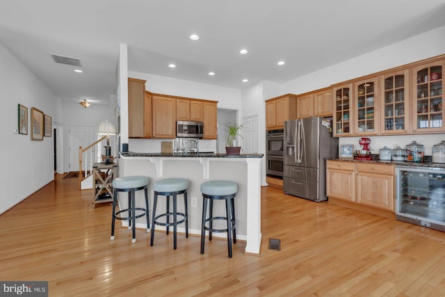 kitchen with dark stone countertops, a breakfast bar area, appliances with stainless steel finishes, wine cooler, and visible vents