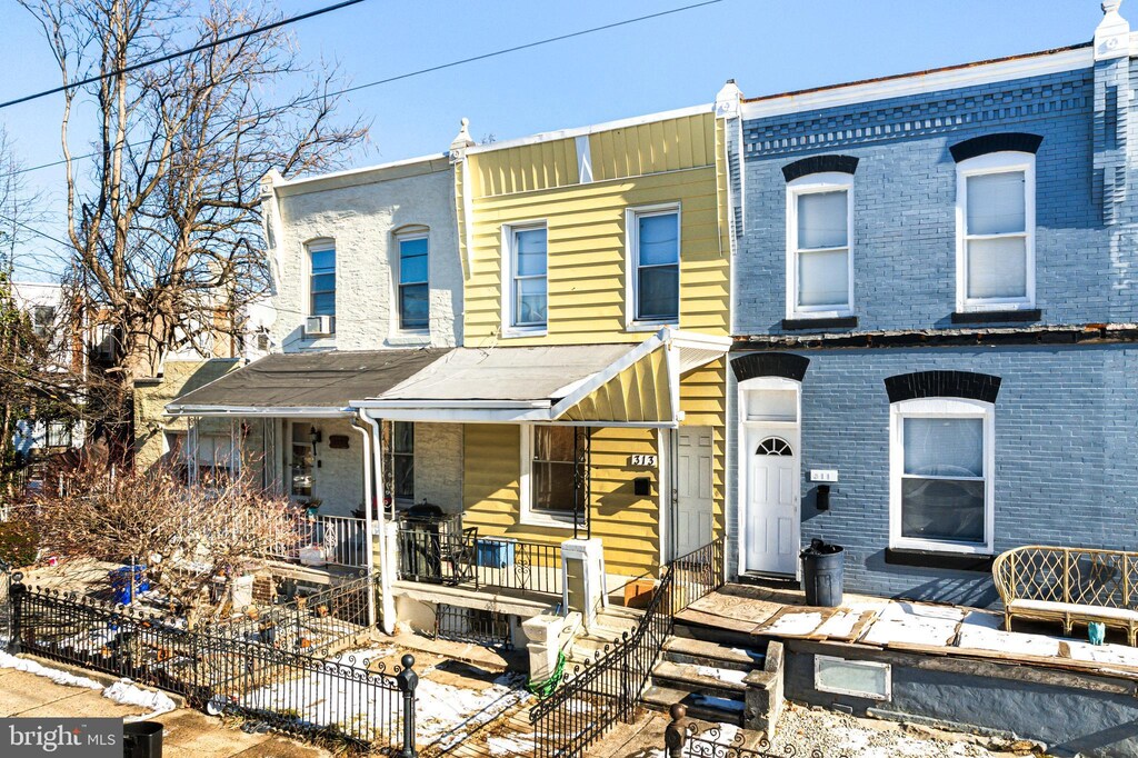 multi unit property featuring covered porch, fence, and brick siding