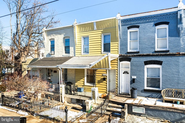 multi unit property featuring covered porch, fence, and brick siding