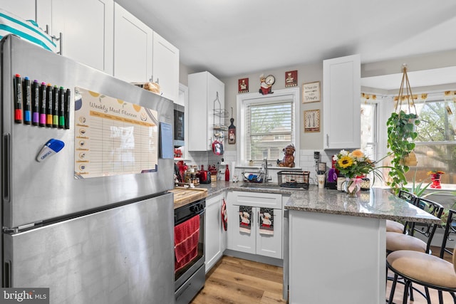 kitchen featuring white cabinetry, a breakfast bar, freestanding refrigerator, and backsplash