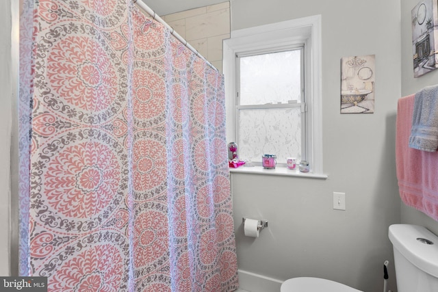 bathroom with a shower with shower curtain, baseboards, and toilet