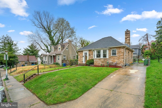bungalow-style house featuring concrete driveway, a front yard, fence, and a gate