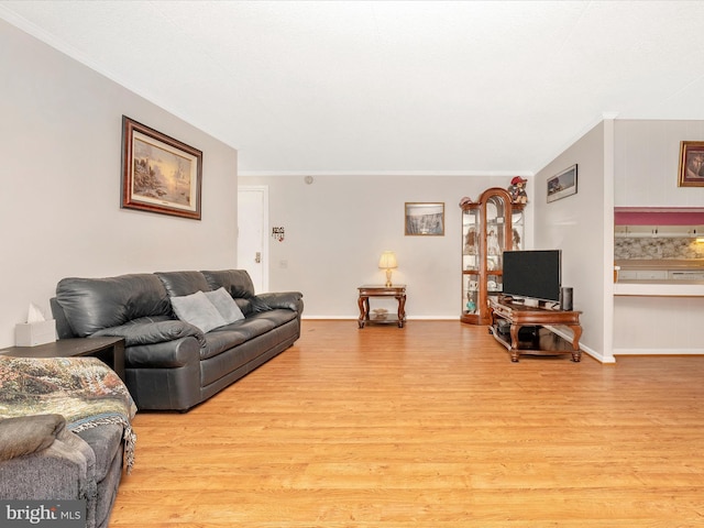 living area featuring light wood-style flooring and ornamental molding
