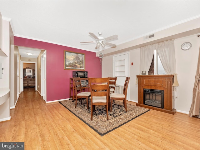 dining area with baseboards, crown molding, a ceiling fan, light wood-style floors, and visible vents