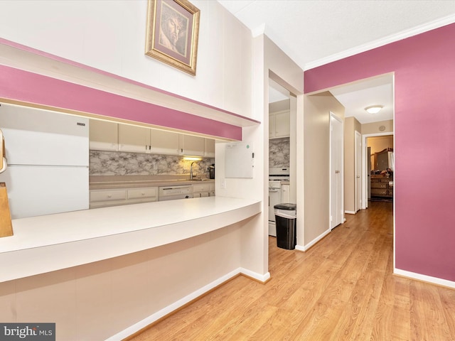 hall featuring baseboards, light wood-style flooring, a sink, and crown molding