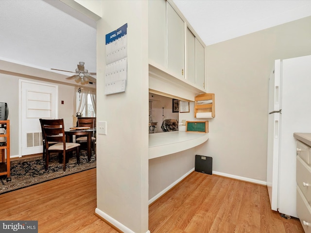 kitchen featuring light wood-style floors, baseboards, freestanding refrigerator, and ceiling fan
