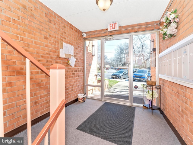 doorway to outside featuring mail area, carpet flooring, and brick wall