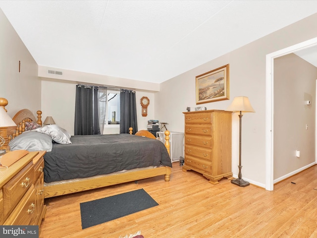 bedroom with light wood-style floors, baseboards, and visible vents