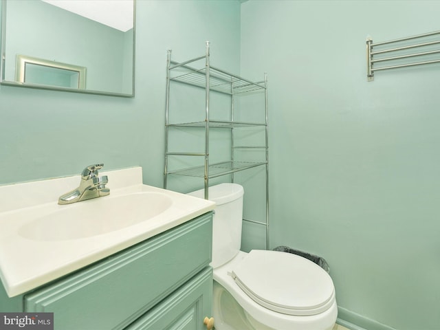 half bathroom with vanity, baseboards, and toilet