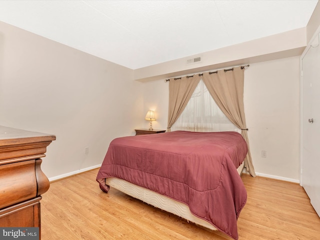 bedroom featuring light wood finished floors, baseboards, and visible vents