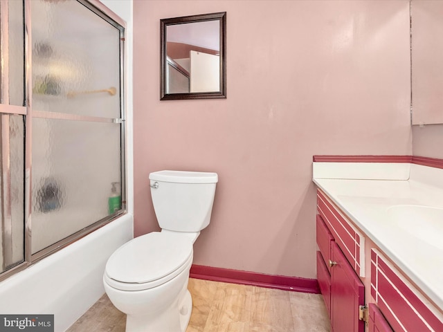 full bathroom featuring bath / shower combo with glass door, vanity, baseboards, and toilet